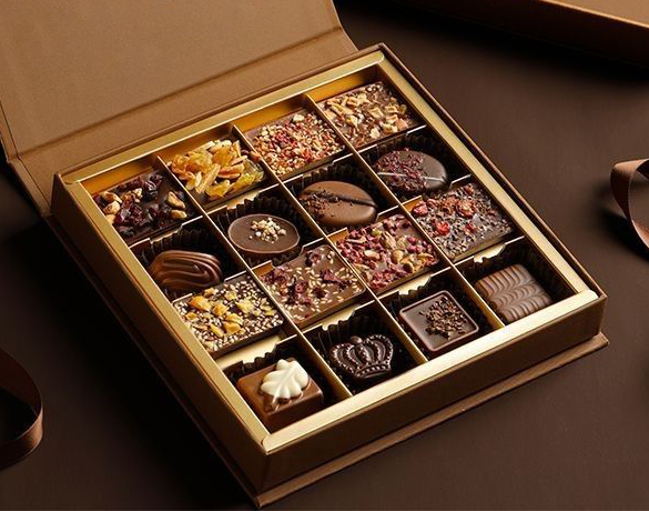 Concept image of a luxury chocolate rigid box with a gold grid insert creating individual compartments, designed for premium gifting presentation—Shabouk solutions in the UAE.